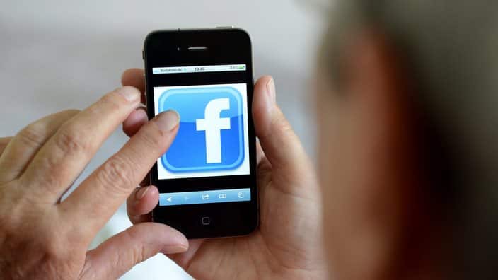 An old woman is using Facebook on her phone. 