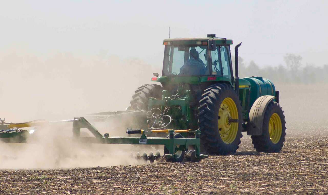 Representational image of a farmworker with a tractor.