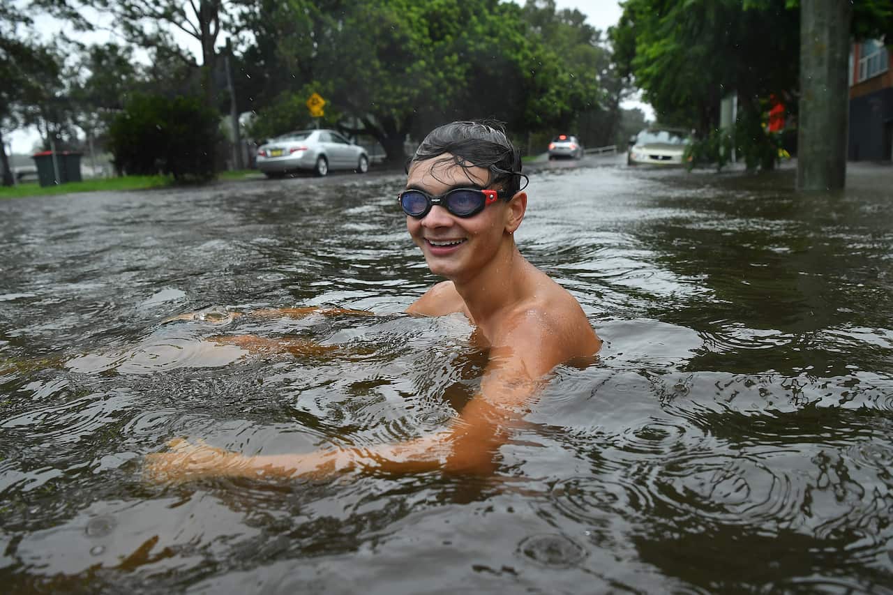 A boys sits in floodwater in the Sydney suburb of Tempe.