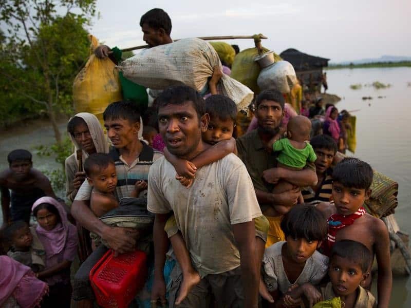 File image of Rohingya Muslims carry their young children over water.