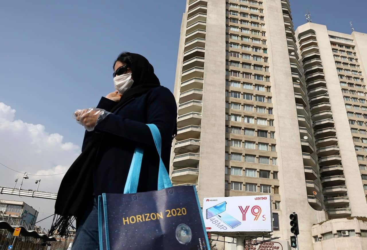 A pedestrian wearing a face mask crosses a street in northern Tehran.