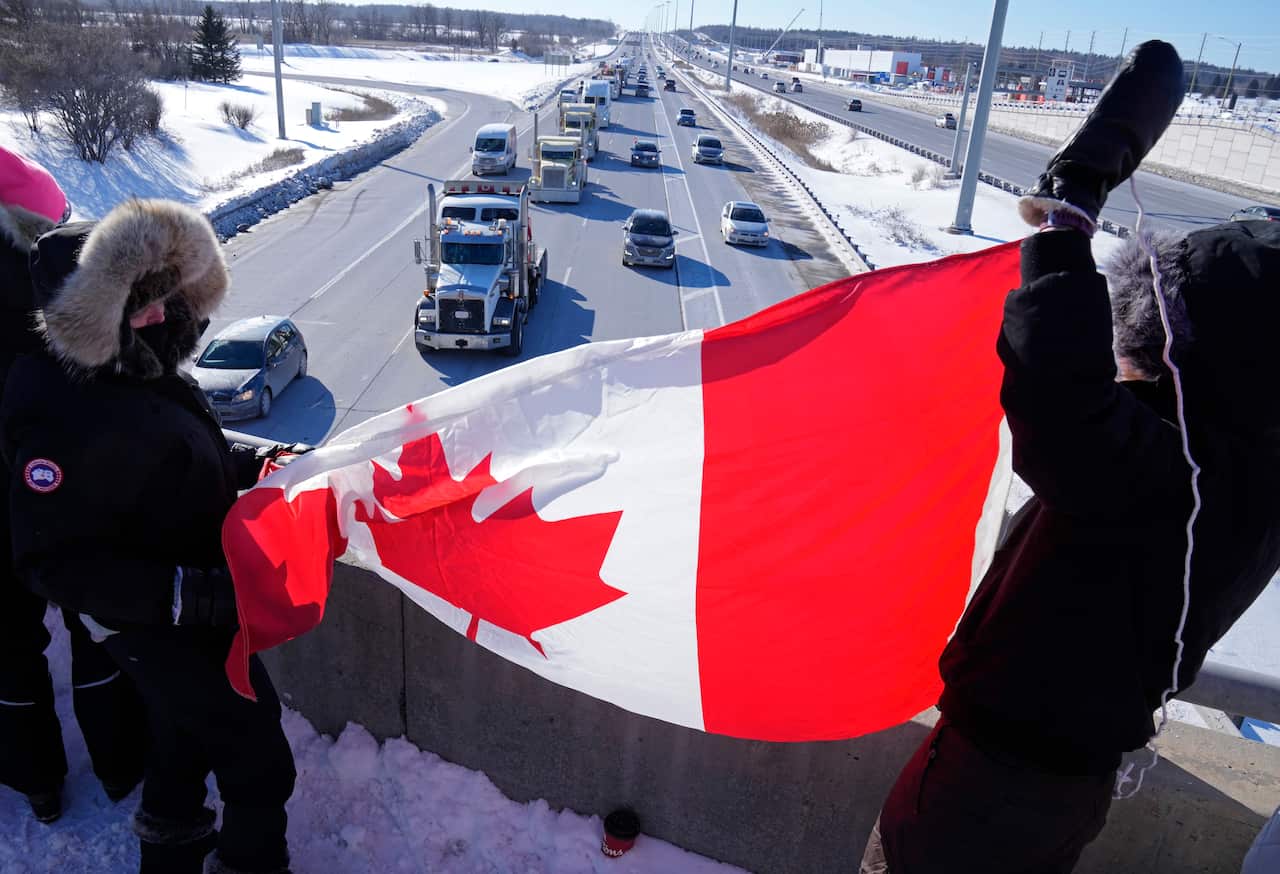 Supporters wave Canadian flags on an overpass