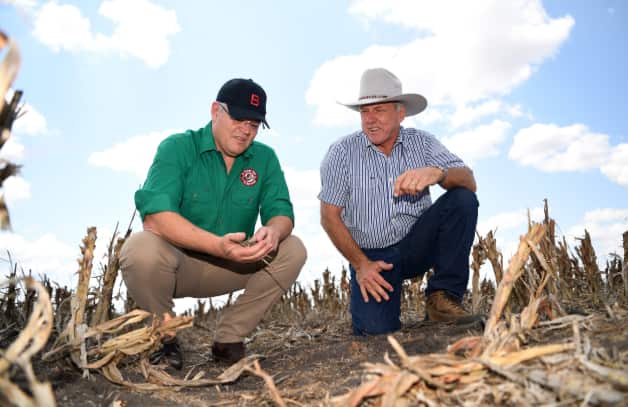 Prime Minister Scott Morrison (left) inspects the dry soil with farmer David Gooding on his drought-affected property near Dalby, Queensland. AAP