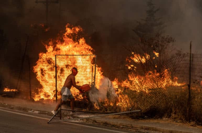 A volunteer tries to put out the fire by throwing dirt on it in Athens, Greece on 6 August, 2021.