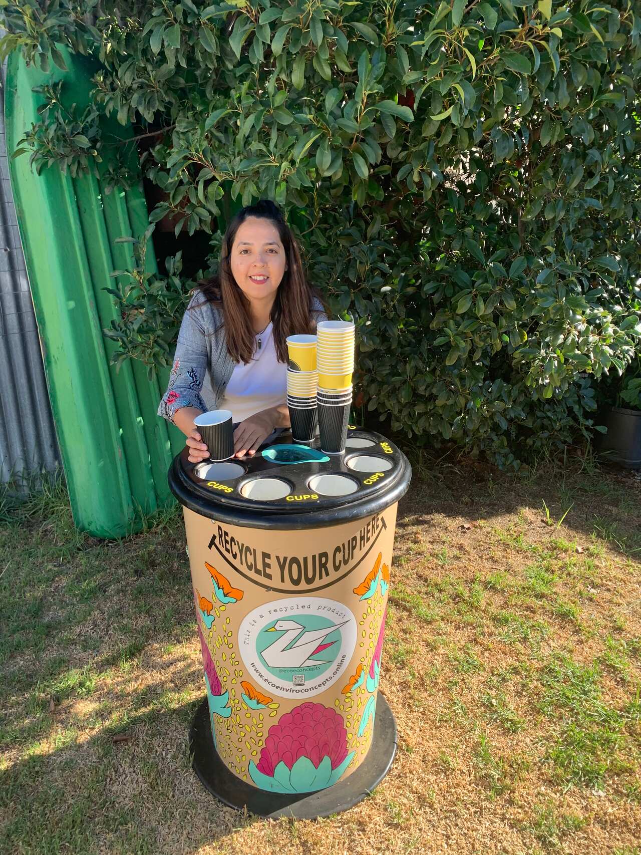 Flavia con réplica de un vaso de café gigante que diseñaron para recoger los vasos de café descartables.
