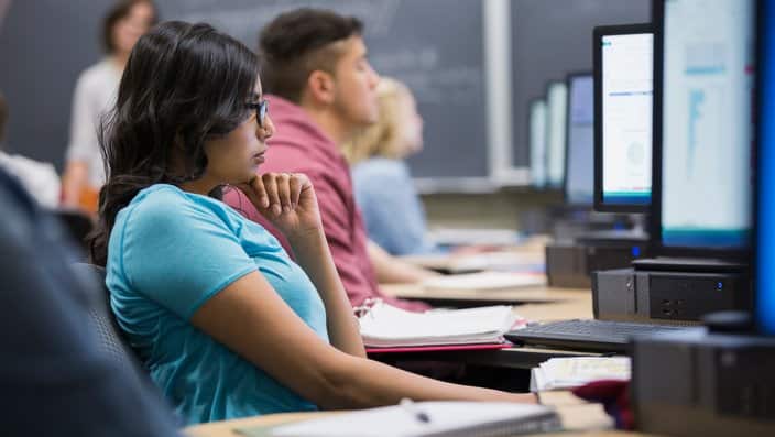 College students studying at computers in classroom