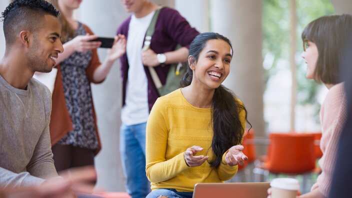 Smiling college students talking and drinking coffee in commons