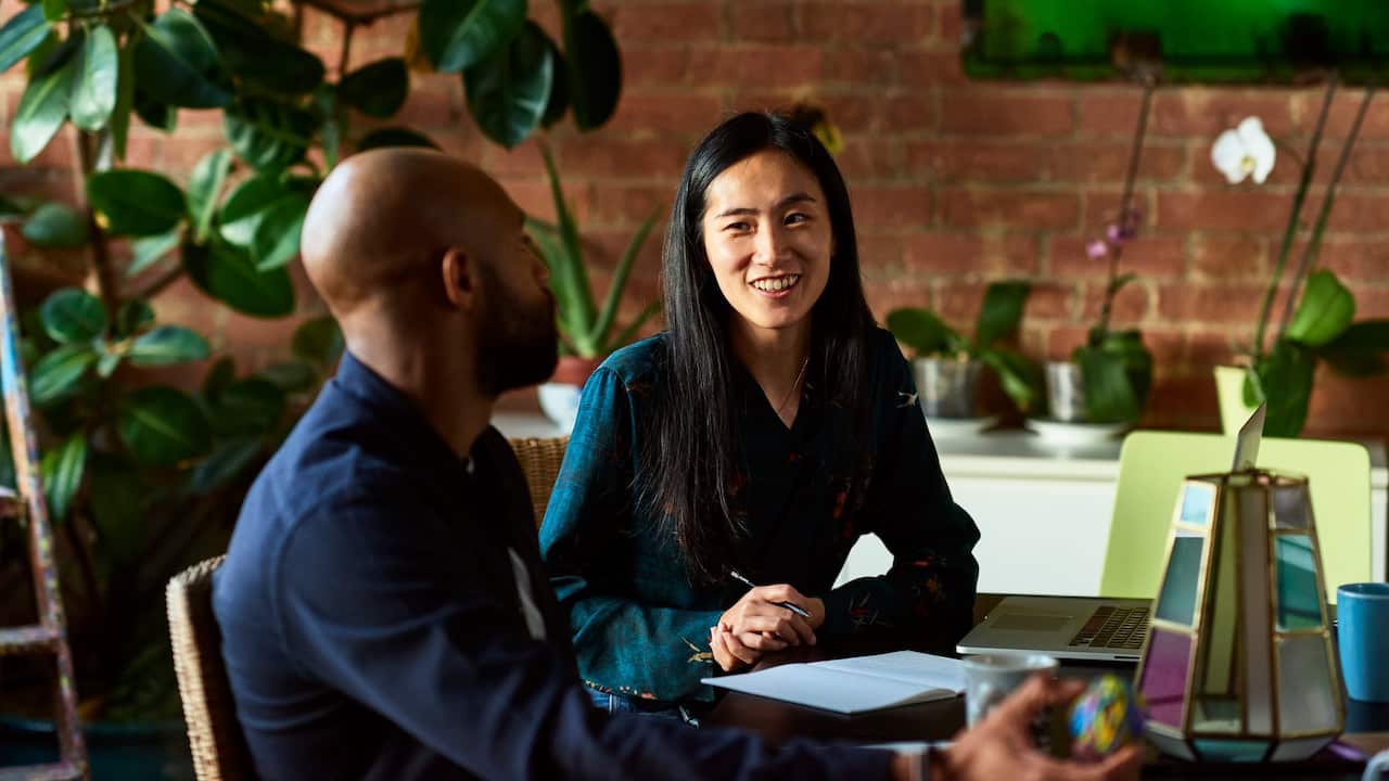 Mid adult Asian woman smiling towards male colleague