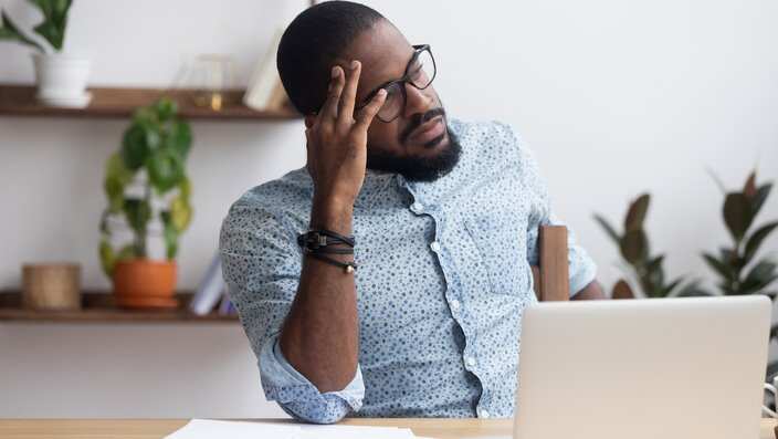 Serious thoughtful african businessman sitting at desk