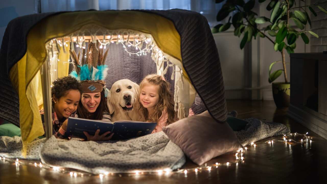 Family reading a book in a tent at home 