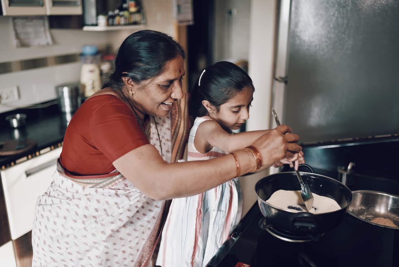 Young girl helping her grandmother while working in the kitchen