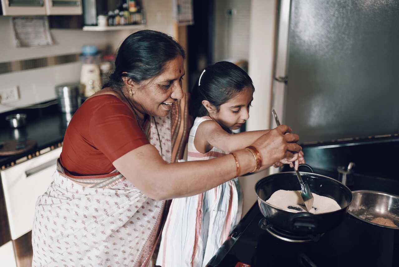 Young girl helping her grandmother while working in the kitchen