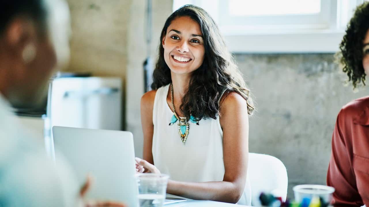 Smiling businesswoman in discussion with colleagues during meeting in office conference room