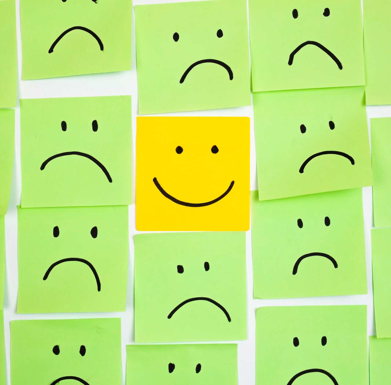 Sad faces on sticky notes and one happy