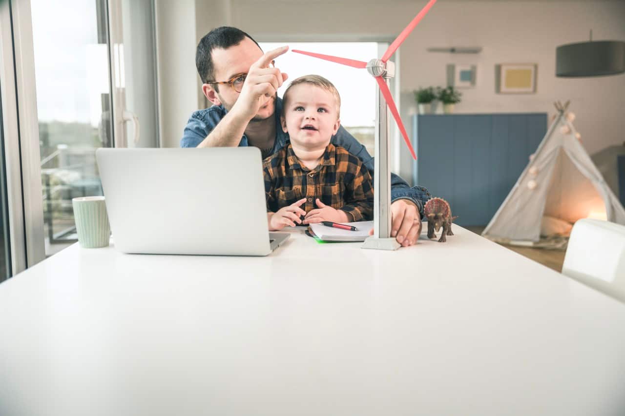 Father and son at home with wind turbine model on table