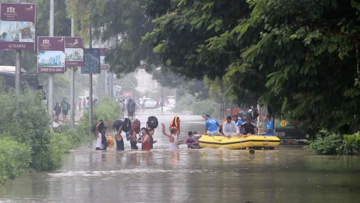People wade in floodwaters to board a rescue boat of the Disaster Response Force (DRF) of the Gujarat state, in Vadodara.