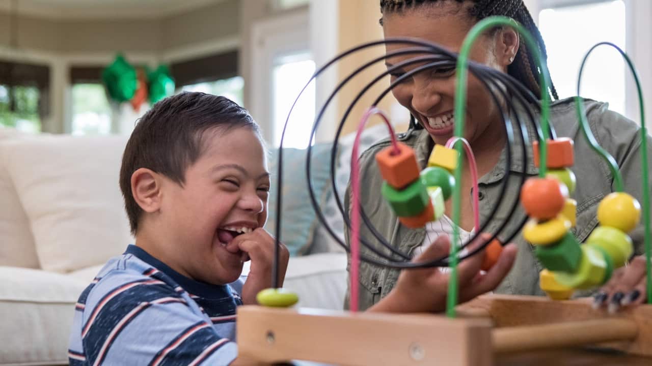 Mom and her special needs son play in the living room. 