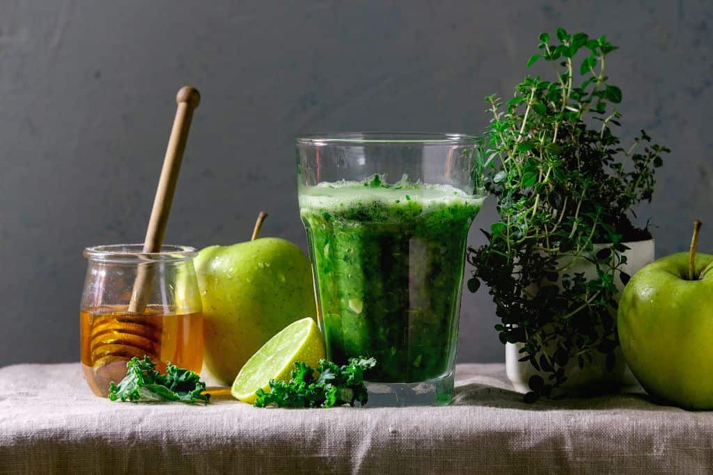 Green spinach kale apple honey smoothie in glass on linen table cloth with ingredients above, Healthy organic eating. (Photo by: Natasha Breen/REDA&CO/Universal Images Group via Getty Images)