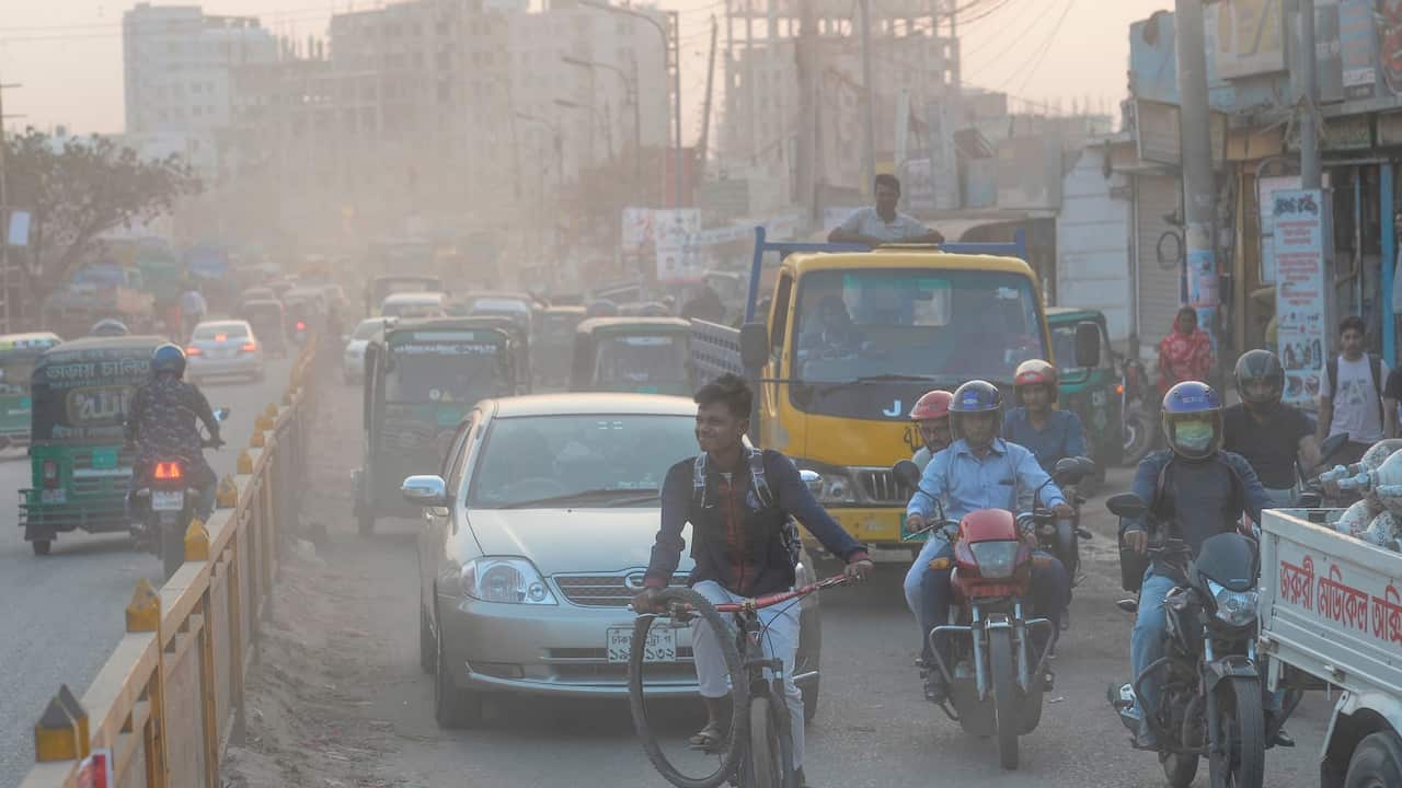 Commuters drive and ride on a road under heavy smog conditions in Dhaka on November 26, 2019. 