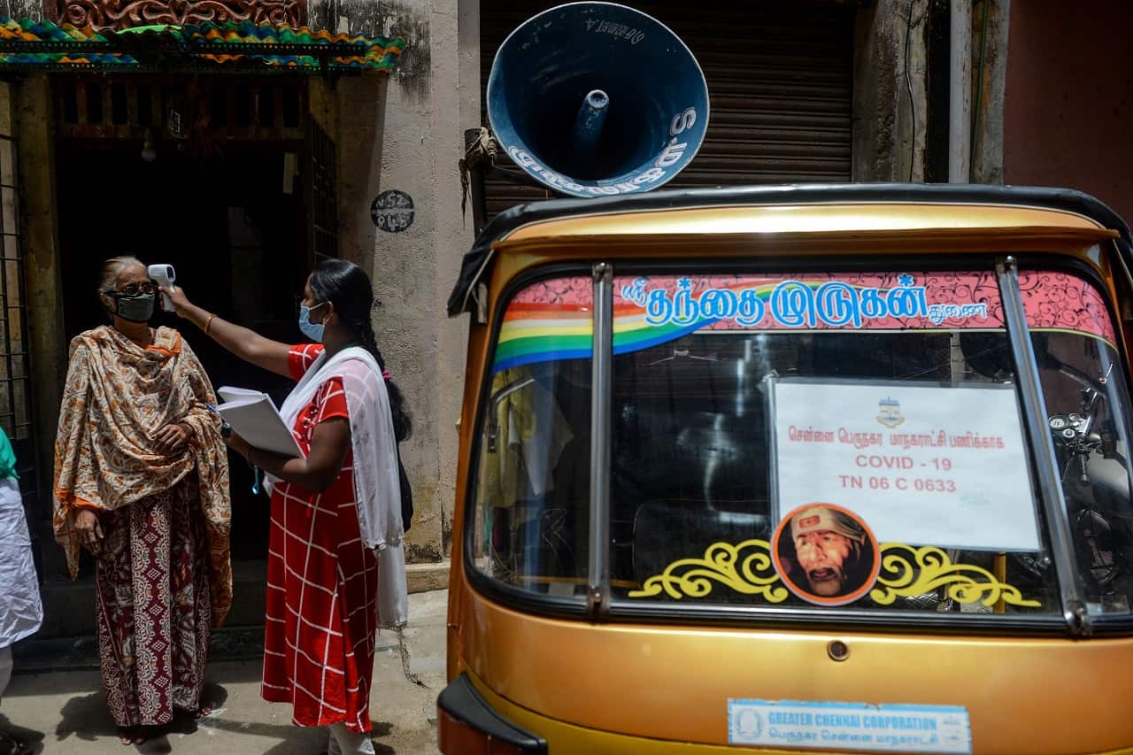 A health worker checks the body temperature of a woman as a preventive measure against the COVID-19 coronavirus in Chennai on July 30, 2020. 