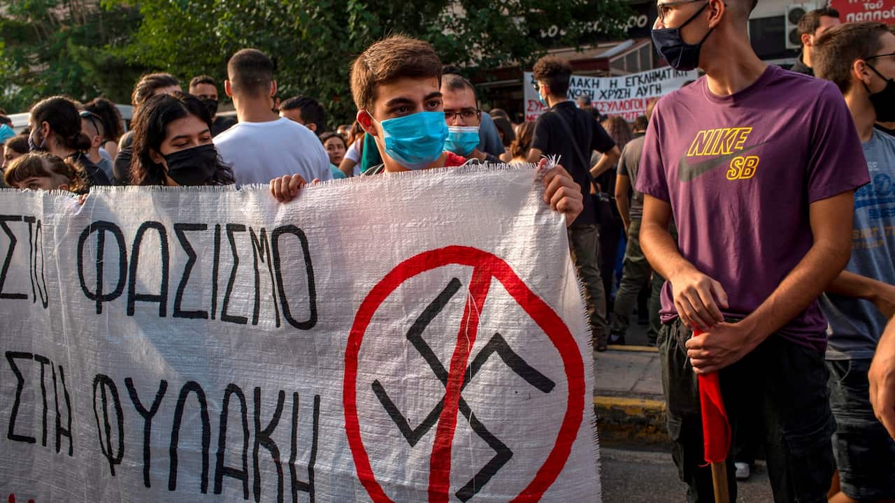 Protesters hold a banner with a Nazi swastika logo during a protest on the day of the verdict in the trial of suspected members of neo-Nazi party Golden Dawn. 