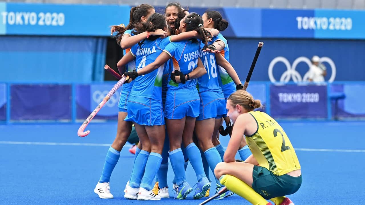 Players of India celebrate after defeating Australia 1-0 as Australia's Renee Taylor squats (R) at the end of their women's quarter-final match of the Tokyo 2020 Olympic Games field hockey competition