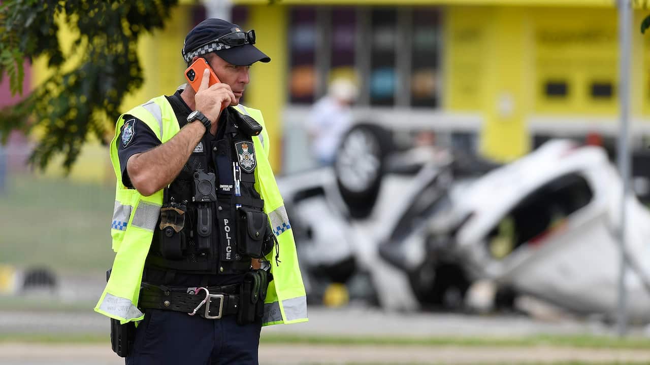 A policeman is seen on his phone at the scene of the car accident on June 07, 2020 in Townsville, Australia.