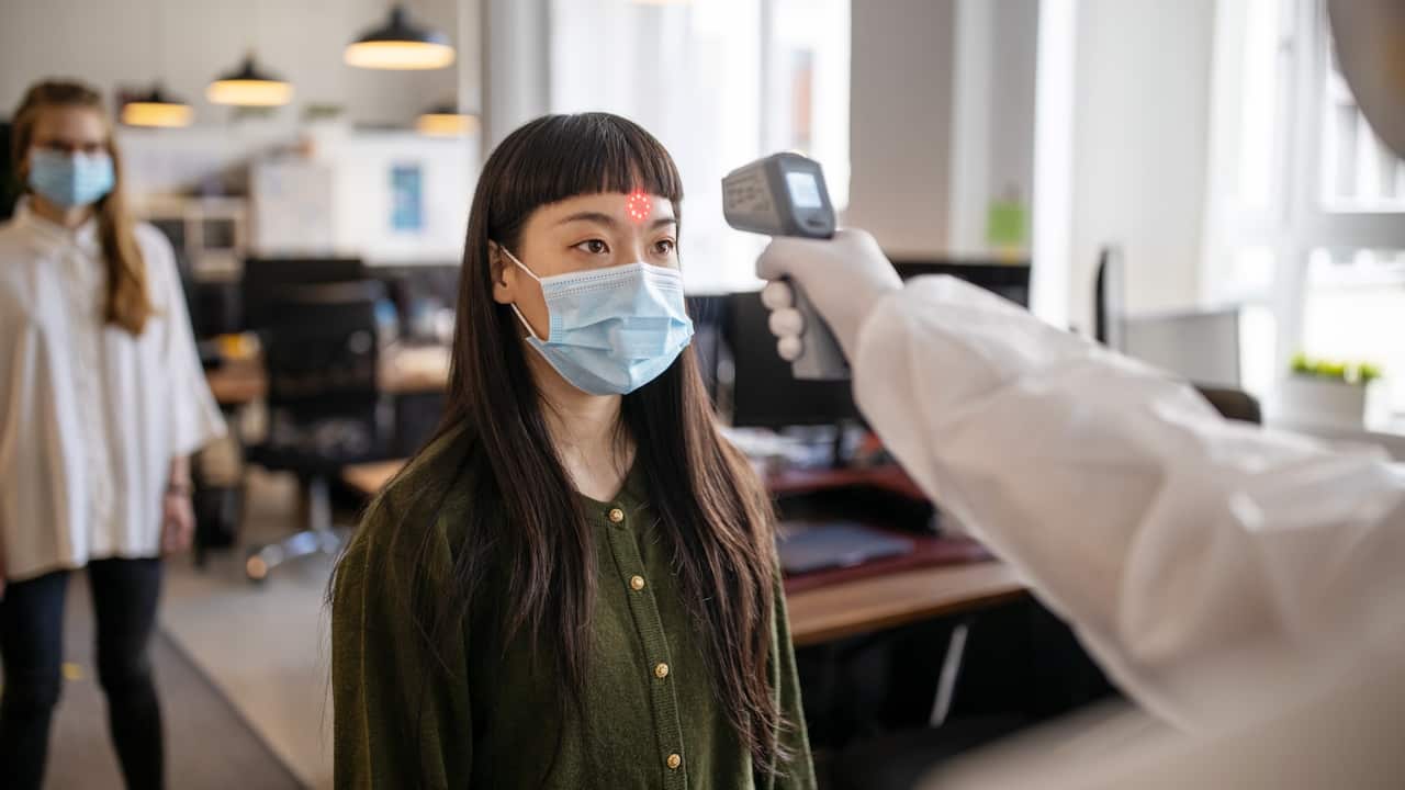 Employees going through mandatory temperature checks in office