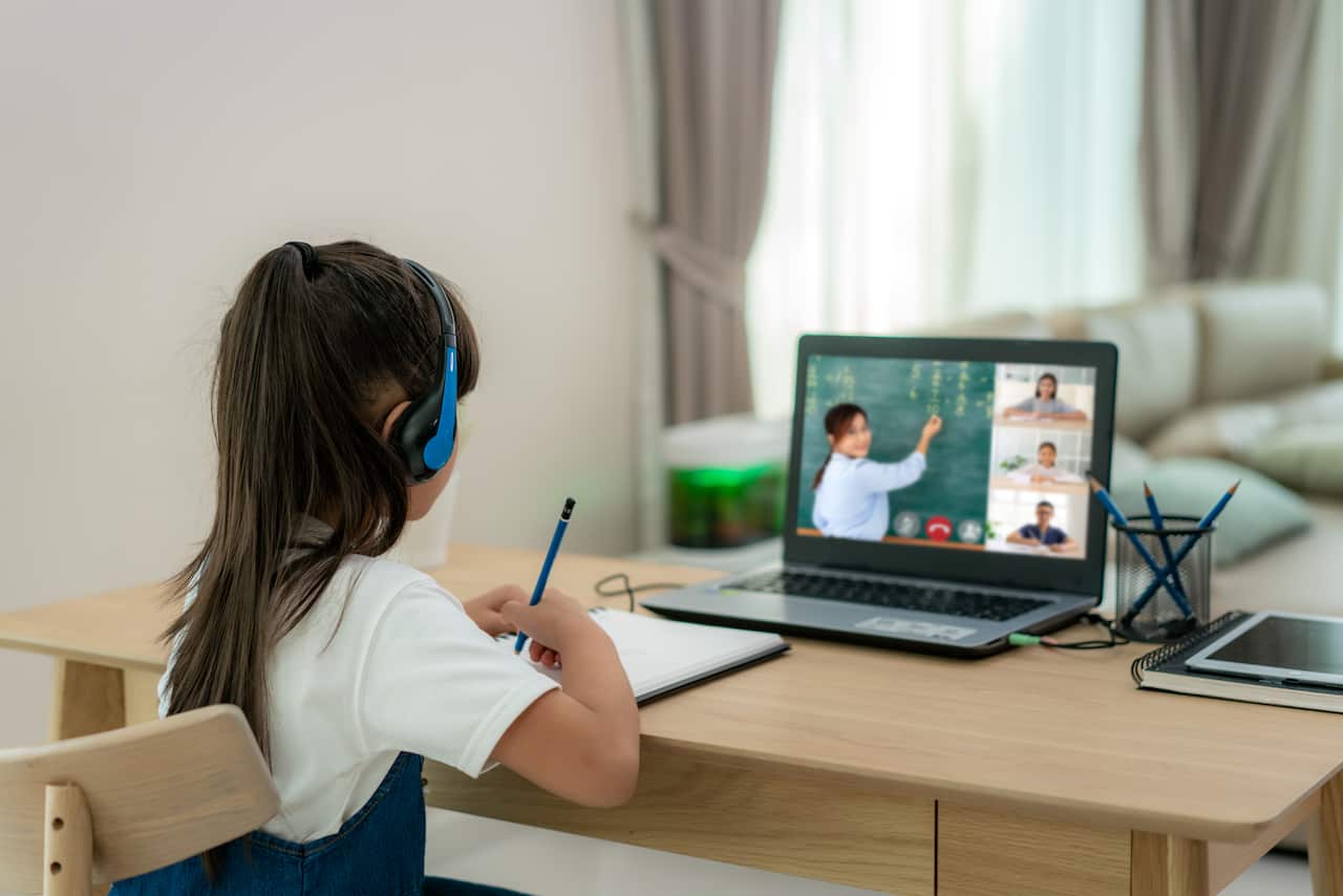 Asian girl student video conference e-learning with teacher and classmates on computer in living room at home. Homeschooling and distance learning ,online ,education and internet.