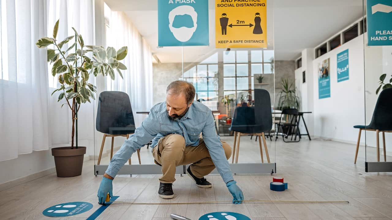 Man applying social distancing sign at office 