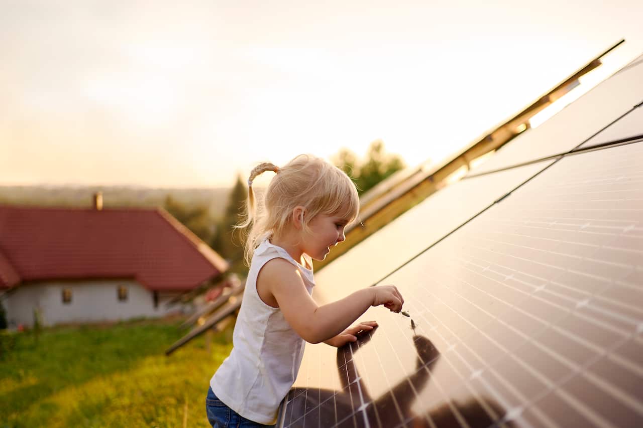 Young girl touching solar panel.