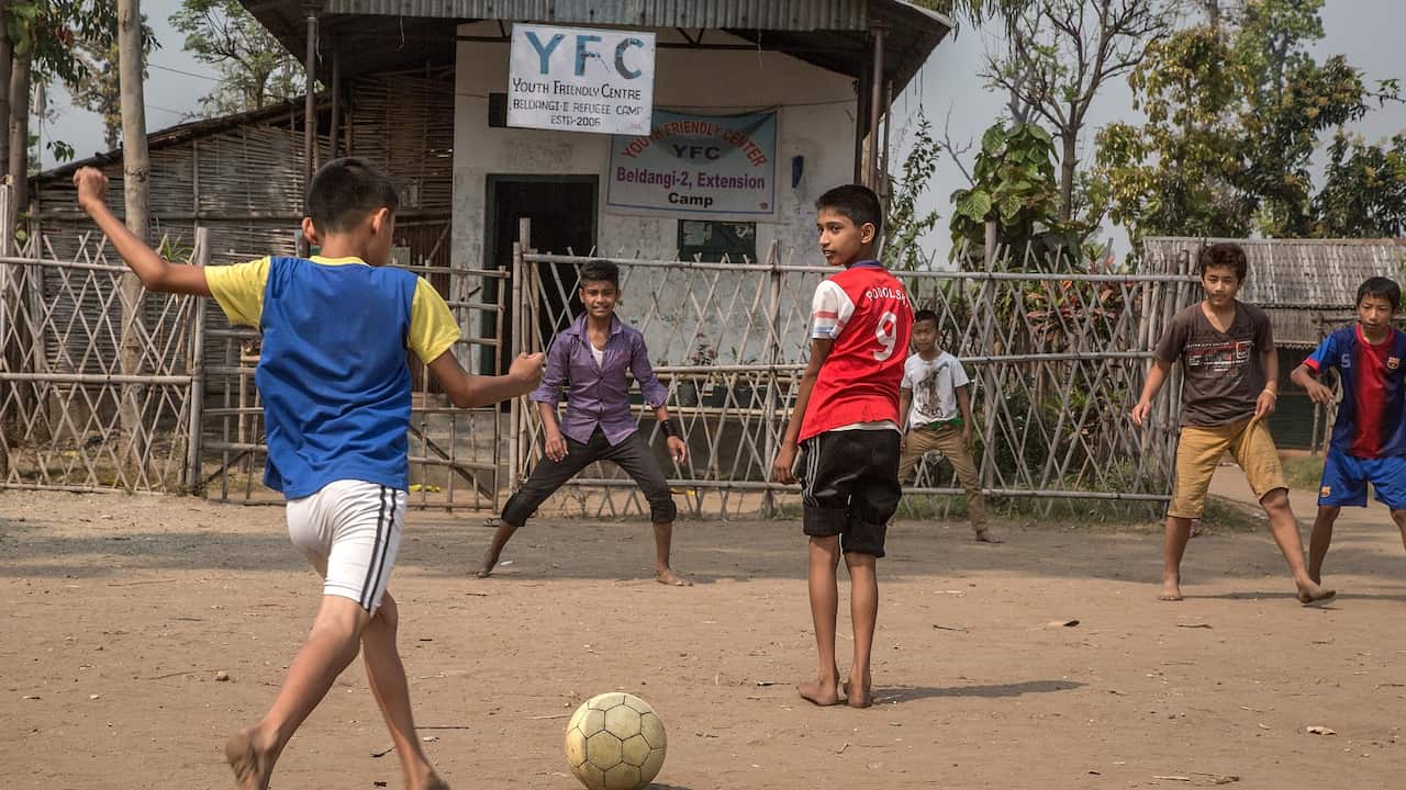A group of young Bhutani refugees play football on a field inside Beldangi 2 refugee camp.
