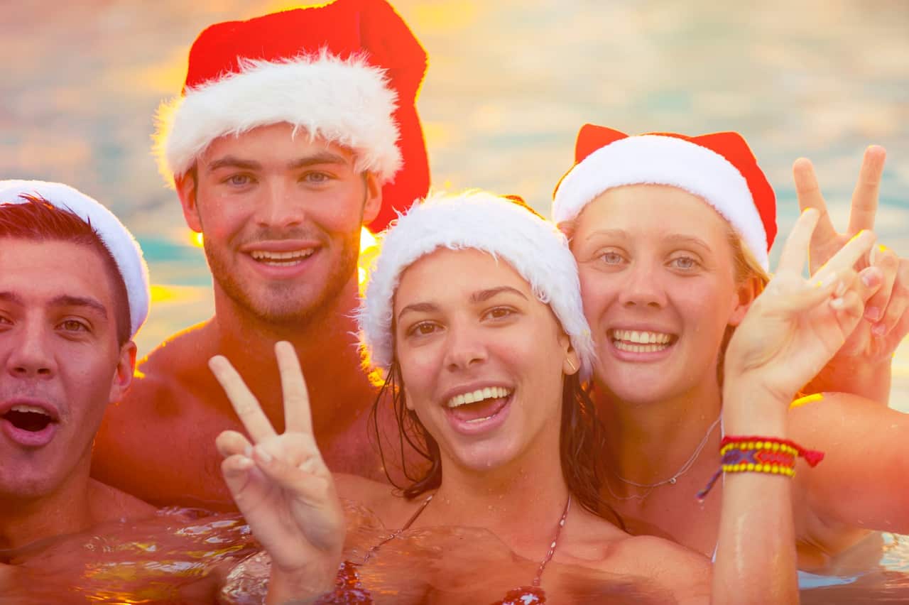 Group of friends swimming with Santa hats.