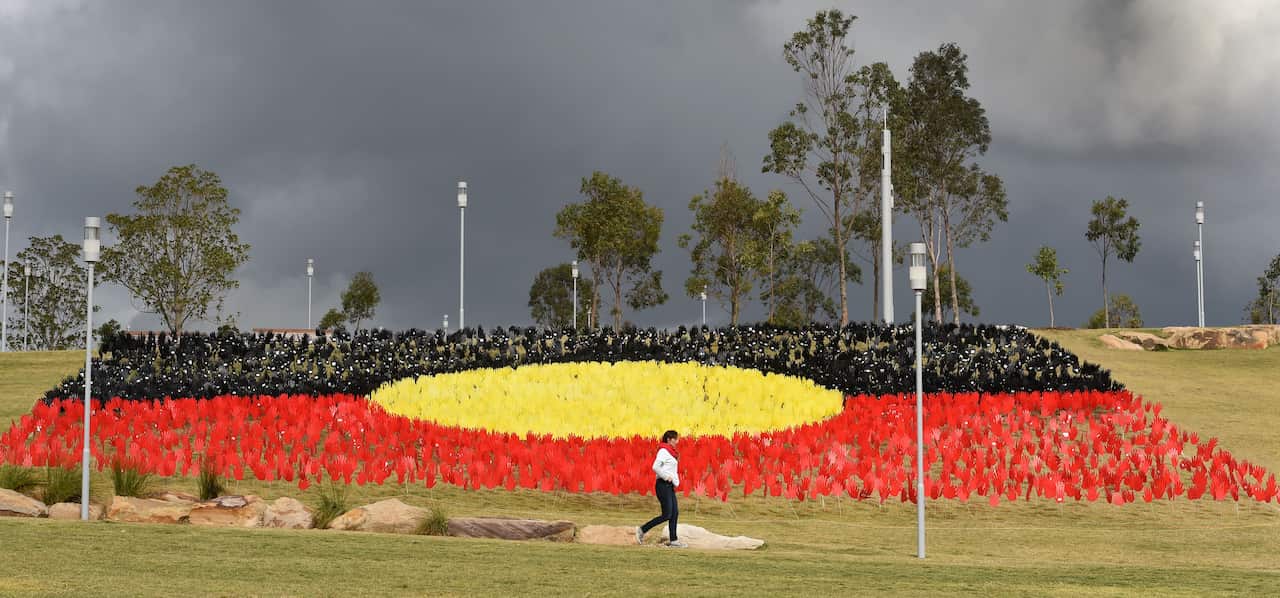 A woman passes a huge art installation called 'Sea of Hands' which consists of thousands of hands in the colours of the Aboriginal flag red, yellow, black.