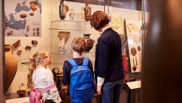 Teacher And Pupils Looking At Artifacts On Display In Museum