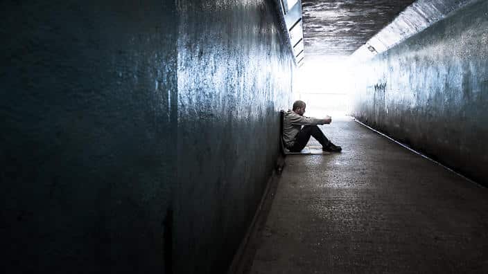 Young homeless adult male sitting and begging in subway tunnel