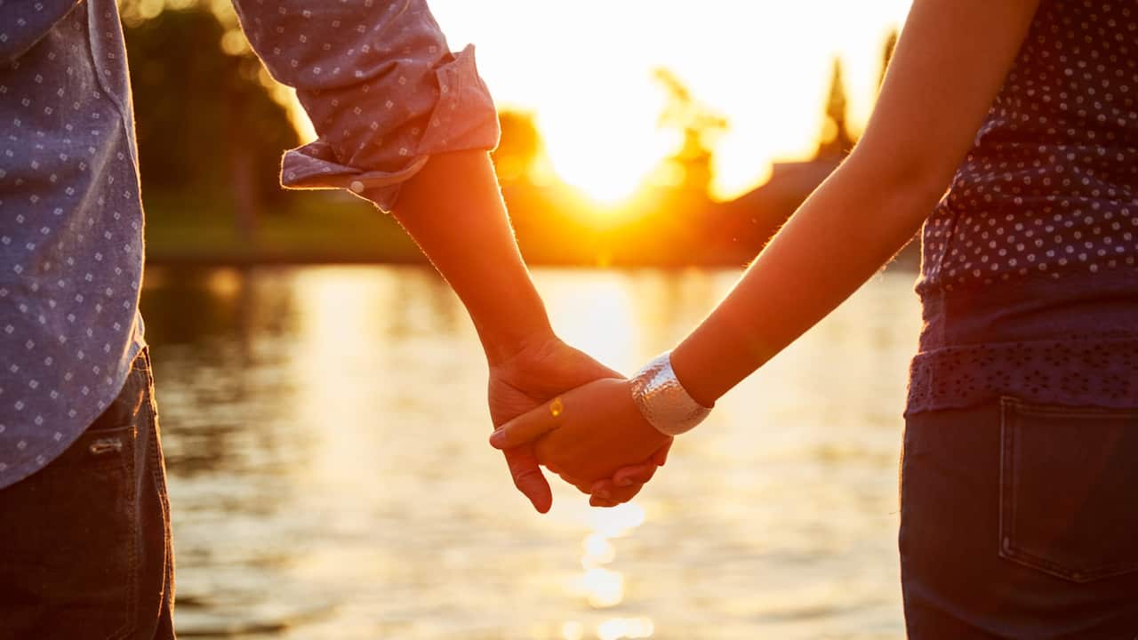 couple holding hands sunset