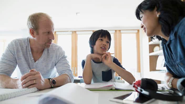 Mother father helping son homework kitchen counter