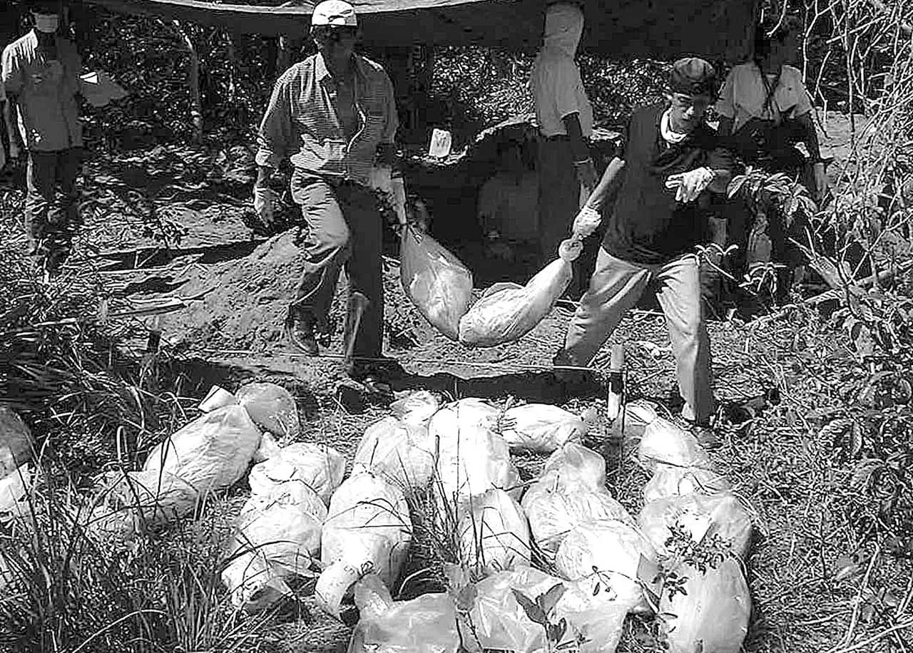 Indonesian rights investigators carries one of the 26 exhumed bodies