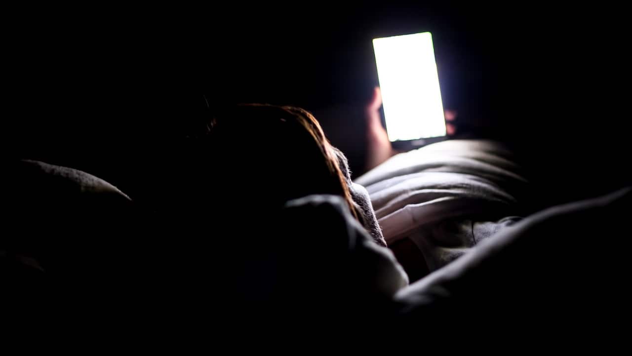 Woman using smartphone for looking up social medial at late night lying in bed, Internet addicted.