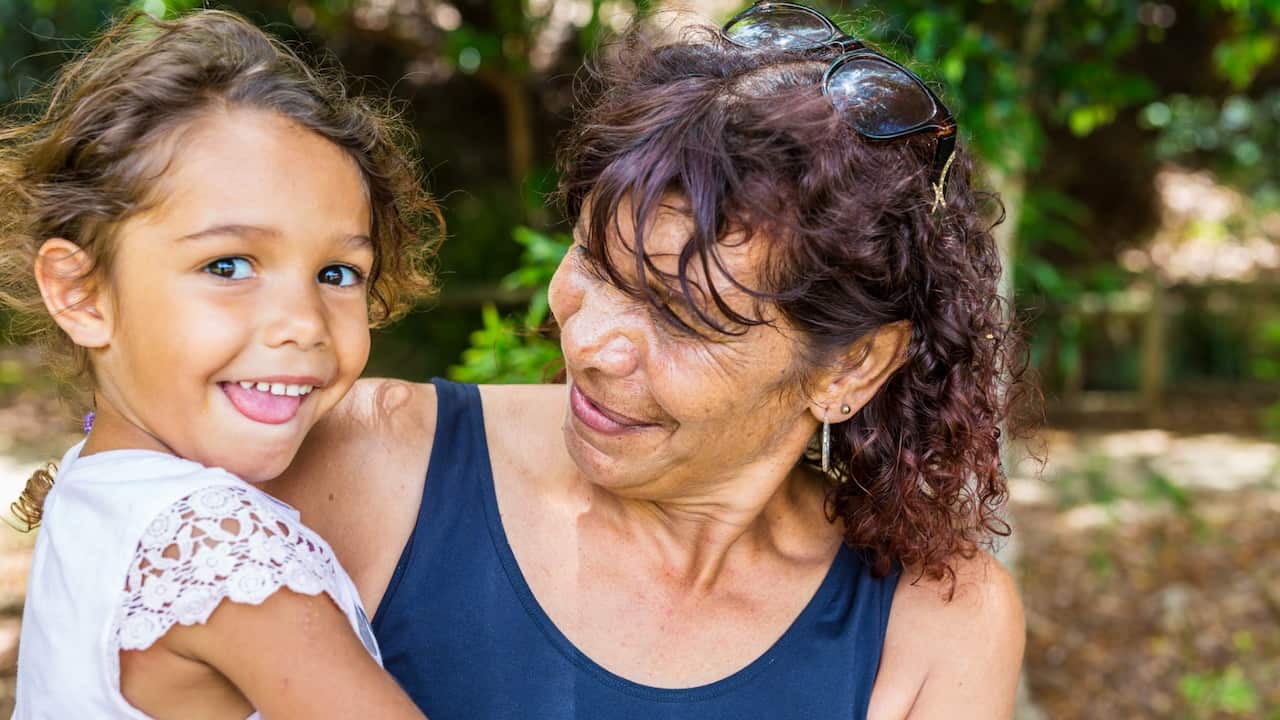 Australian Aboriginal woman giving her granddaughter a hug in the park