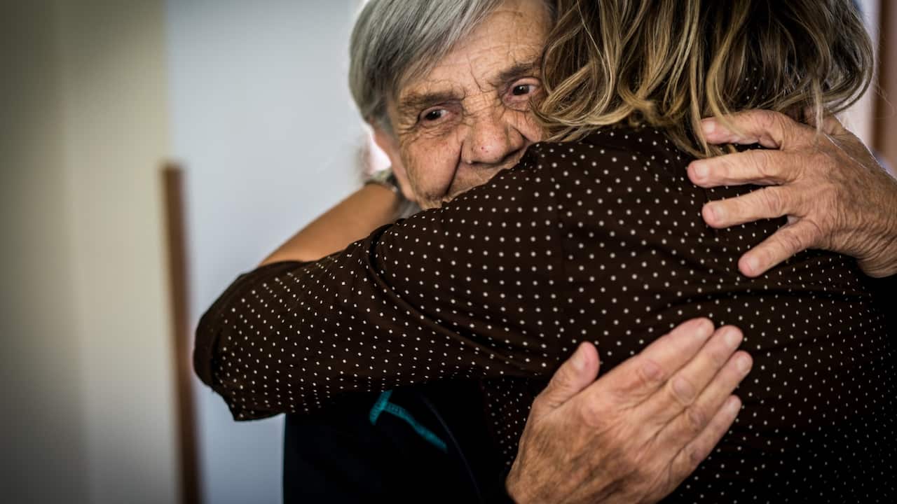 old woman embracing younger woman