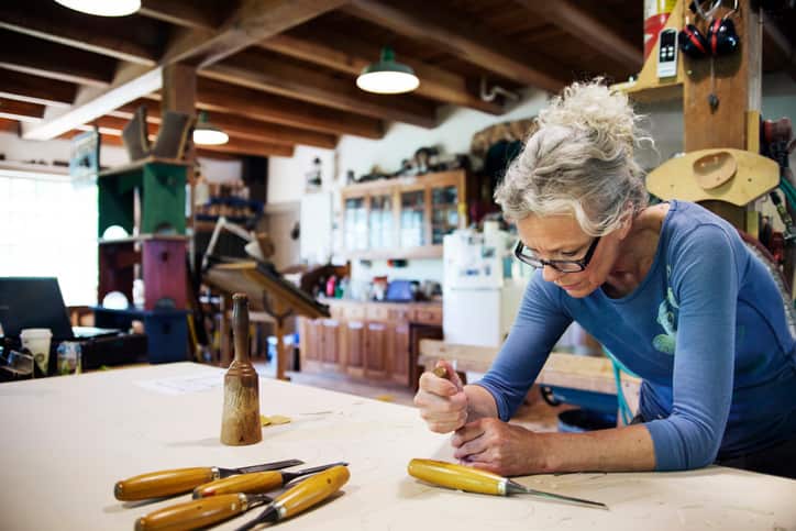 Concentrated female using chisel for shaping wood in workshop