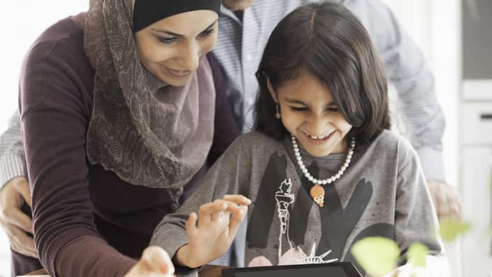 Muslim couple with daughter using digital tablet at home