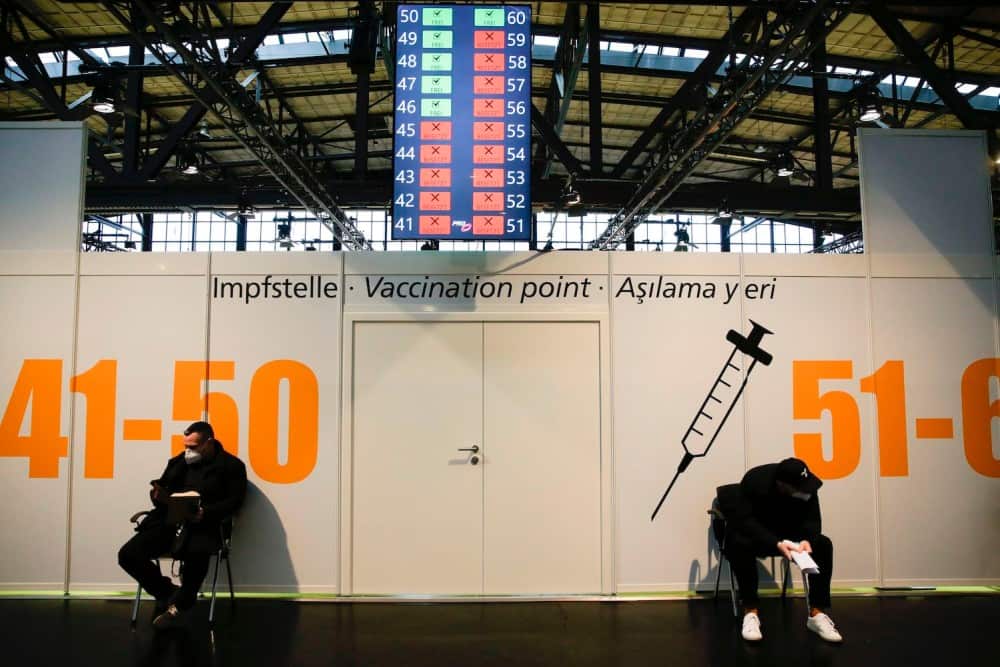 Two men wait for their vaccinations at Treptow Arena’s vaccine center in Berlin