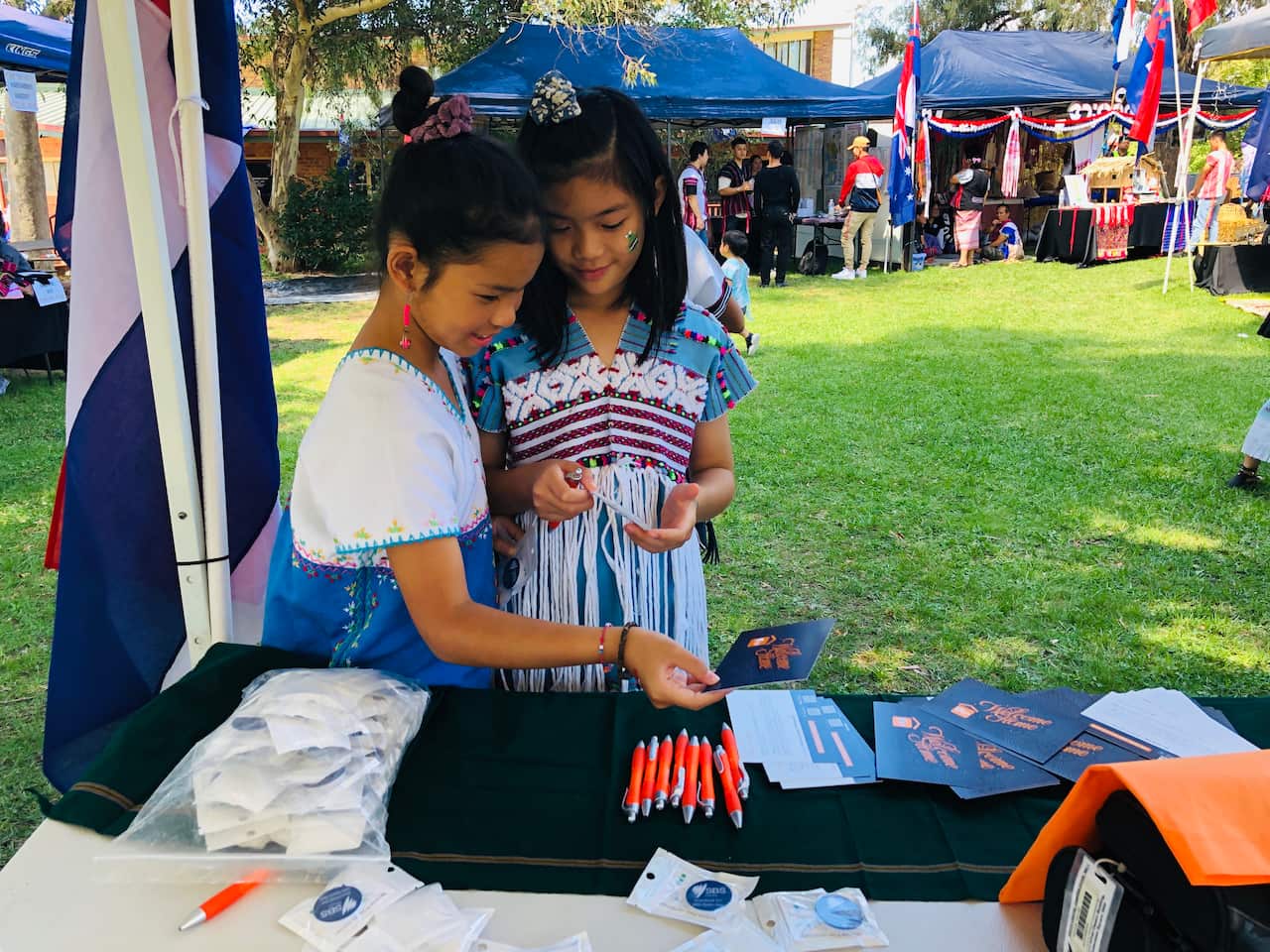 Young Karen girls looking at SBS Karen Program postcard