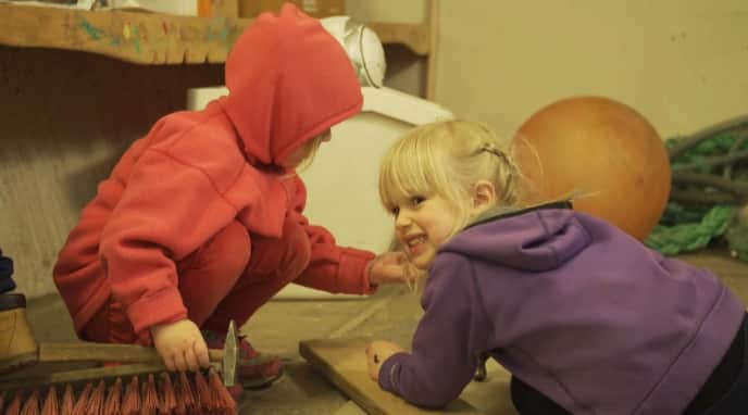 Girls play with a hammer and nails.