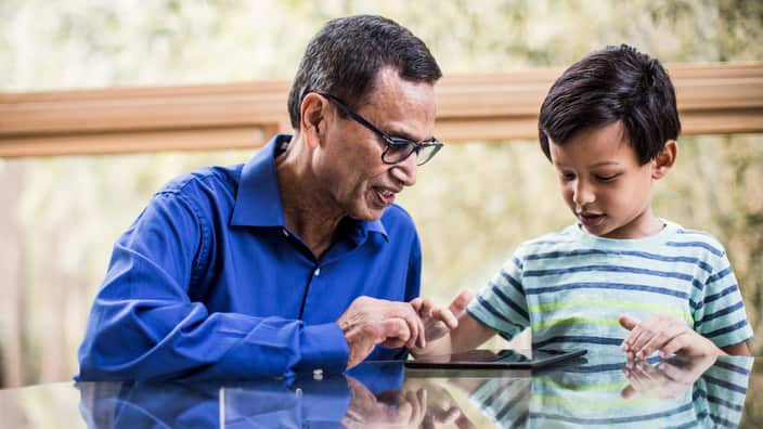 Grandson showing grandfather how to use tablet