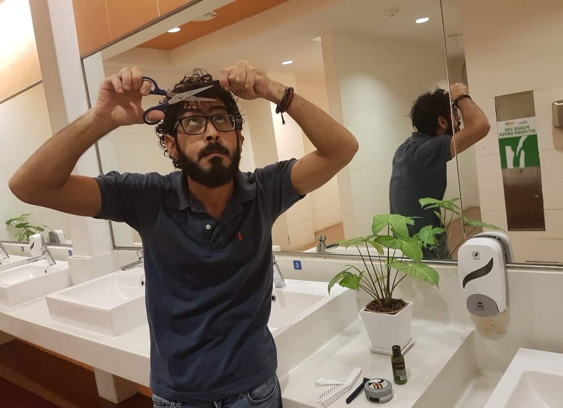Hassan al-Kontar in the airport toilet attempting to cut his hair. Courtesy of Hassan al-Kontar.
