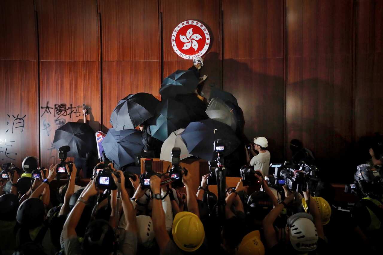 July 1, 2019, file photo, journalists photograph a protester defacing the Hong Kong emblem inside the meeting hall of the Legislative Council in Hong Kong. 